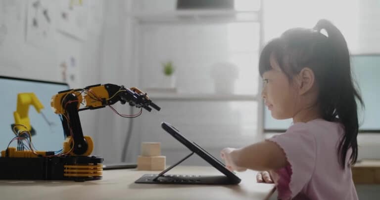 A little girl user her tablet and a robotic arm to create something