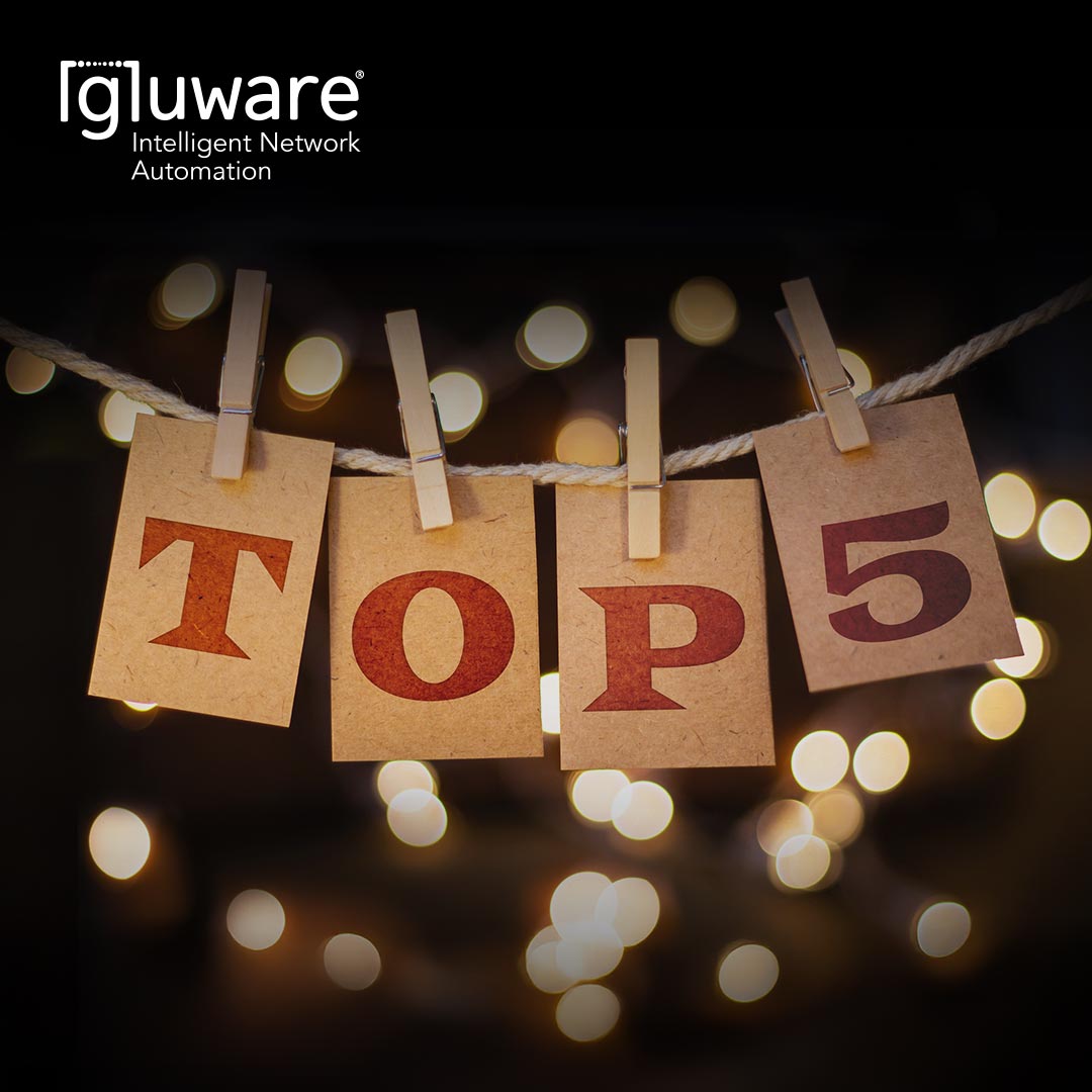 Single letters on cardstock hanging by laundry pins from a line on a Christmas Tree with lights. The words spell "Top 5."